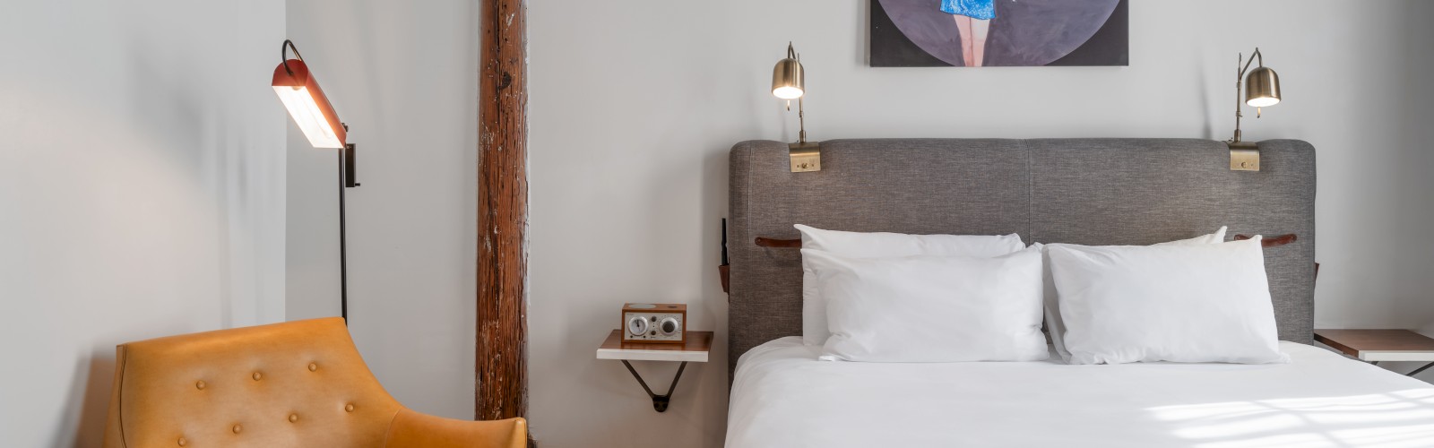 a large white bed with a small yellow chair beside it