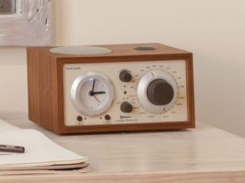 A wooden radio sits beside papers with black brush strokes and paintbrushes, all placed on a light-colored surface, ending the sentence.