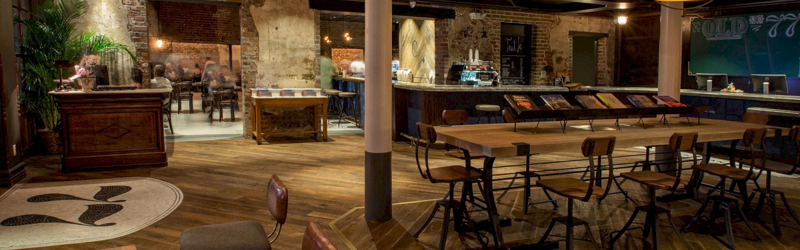 This image shows an inviting, rustic-style lounge area with wooden furniture, multiple tables, chairs, and warm lighting, creating a cozy ambiance.
