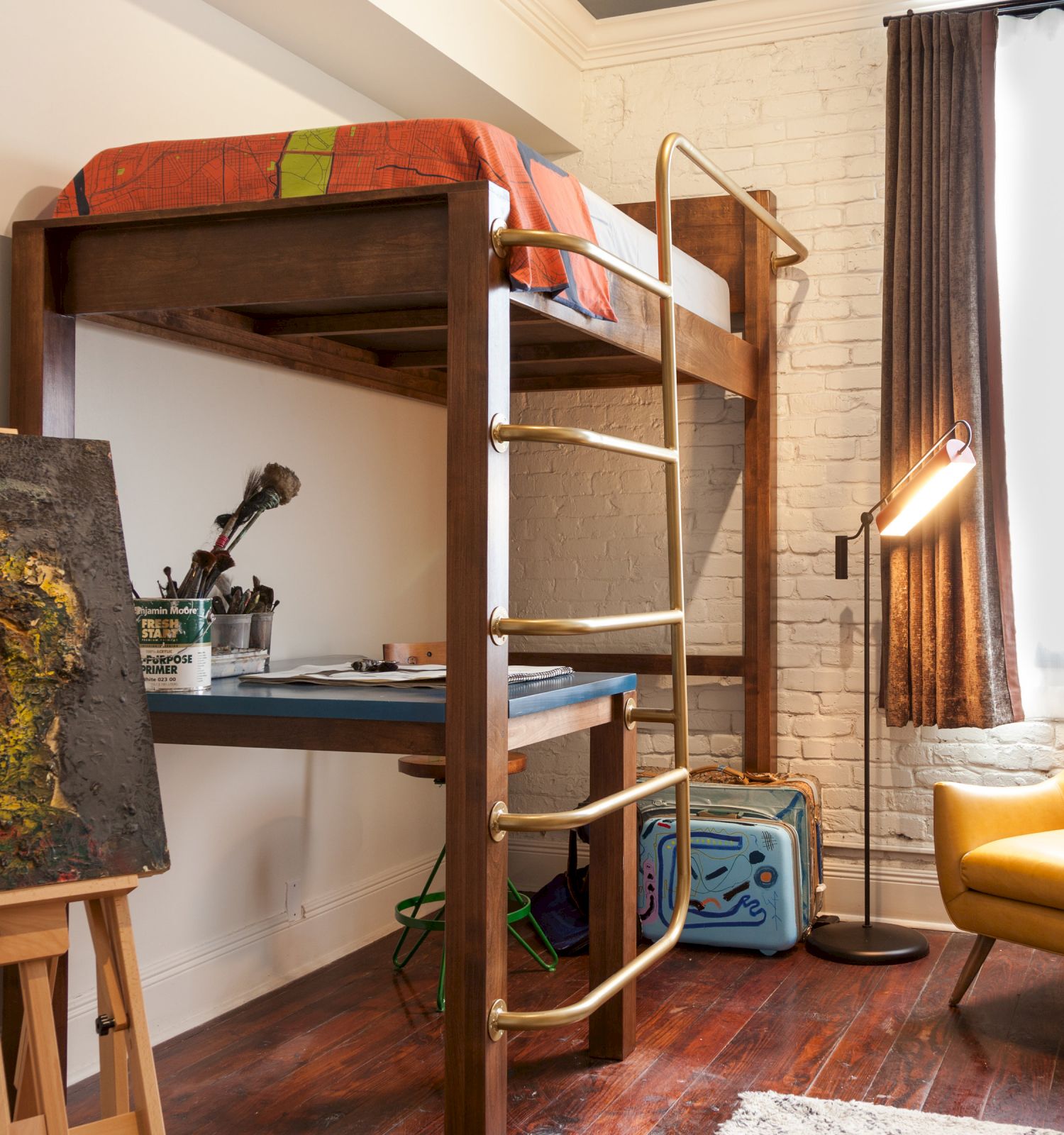 The image shows a room with a loft bed, a desk below, an easel with a painting, a yellow chair, a floor lamp, and a window with curtains.