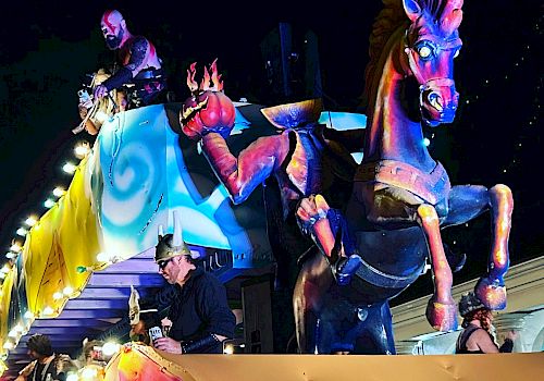 Colorful parade float with mythical horse and festive decorations at night.