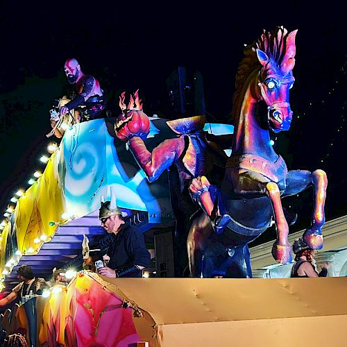 Colorful parade float with mythical horse and festive decorations at night.