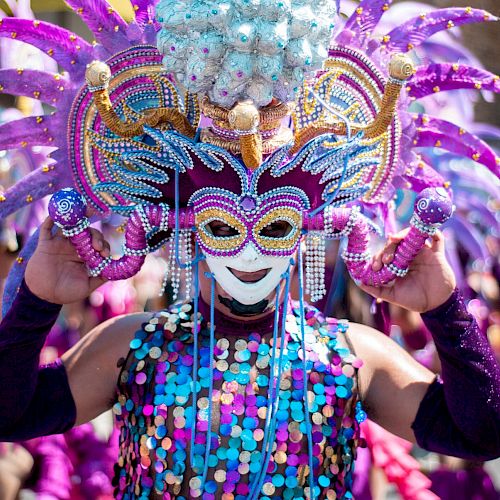 A person in a vibrant carnival costume with a mask and feathers.