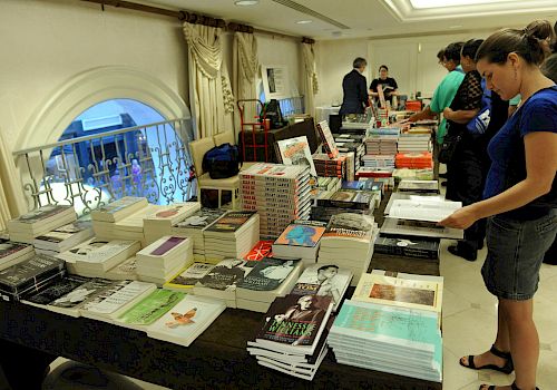 People are browsing books laid out on tables possibly at a book sale or event.