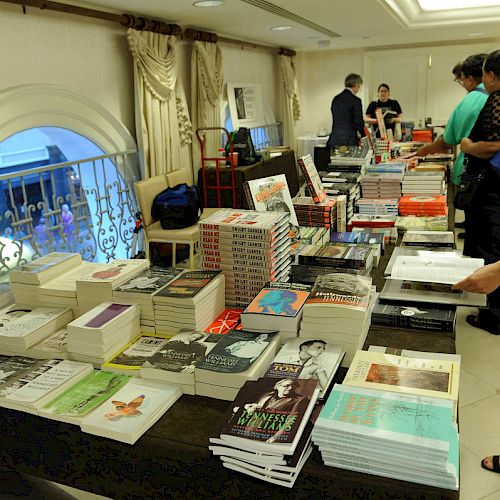 People are browsing books laid out on tables possibly at a book sale or event.