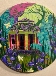 This image shows a circular painting of a quaint house surrounded by vibrant flowers, lush greenery, and butterflies, with a whimsical, colorful background.
