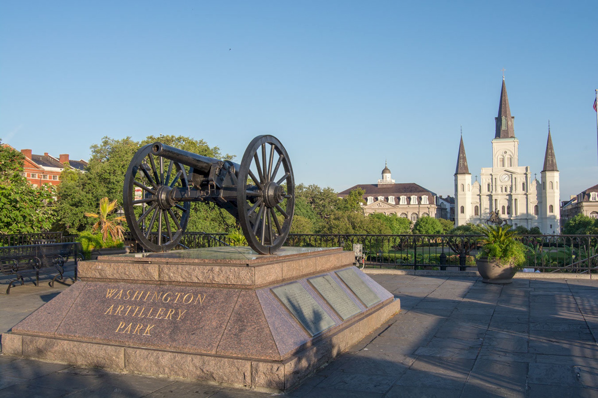 This image shows the cannon monument at Washington Artillery Park with the St. Louis Cathedral in the background on a clear day, ending the sentence.