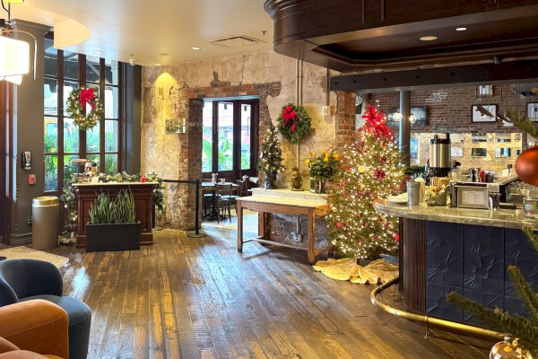 A cozy room decorated for the holidays, featuring a Christmas tree, wreaths, and rustic wooden floors.