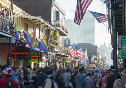 A bustling street scene with crowds celebrating, displaying American and rainbow flags, festive balconies, and city buildings in the background.