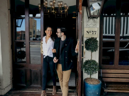 A couple is happily exiting a building named 