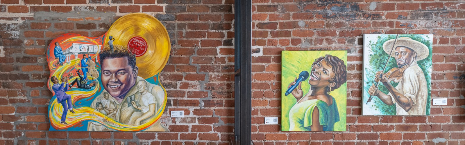 The image shows a brick wall with colorful paintings, a brown leather couch, and a wooden cabinet.