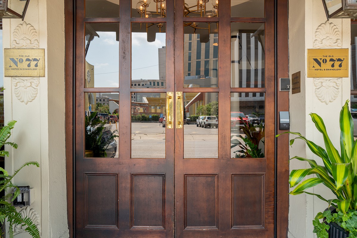 The image shows a set of wooden double doors with glass panels and signs that say 