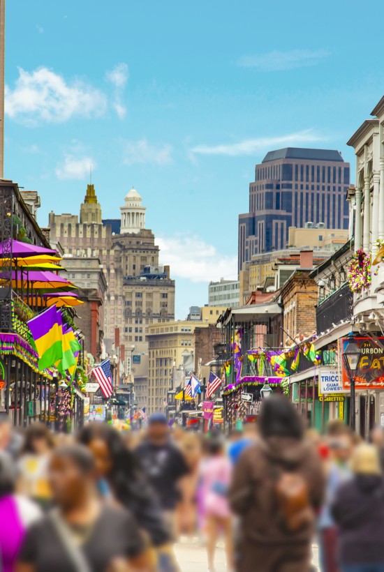 Bustling street scene with colorful storefronts, balconies, and a crowd of pedestrians enjoying a sunny day in a lively urban district.
